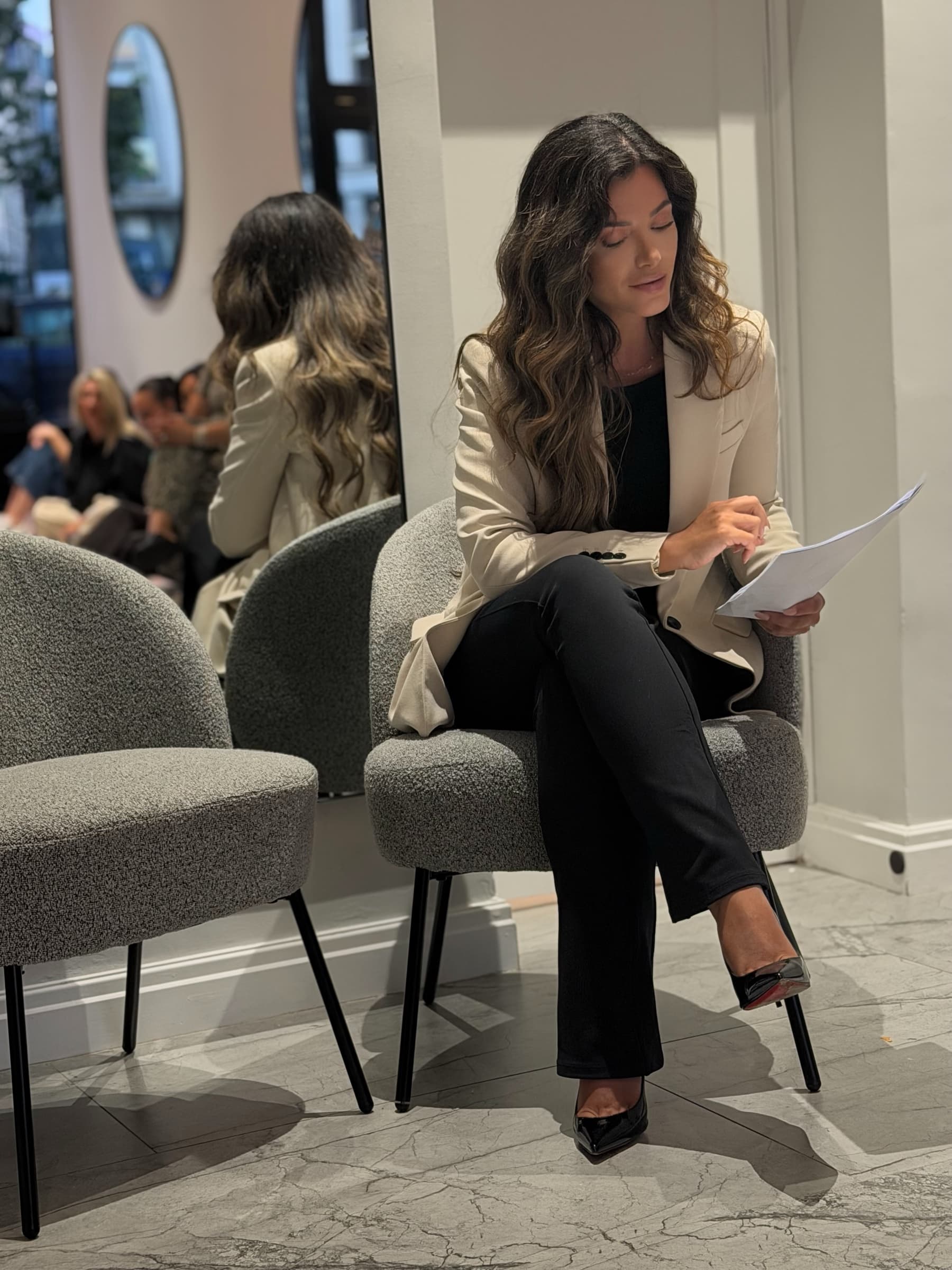 Toska seated in a studio chair, reading through her notes